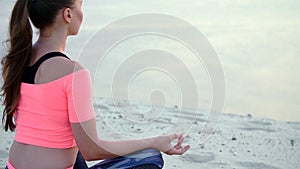 Woman sitting in relaxation yoga pose at the sea beach. Closeup