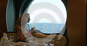 Woman sitting in restaurant on a cruise ship. Cruise liner at ocean.