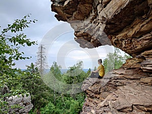 Woman sitting on a rock in the forest and enjoying the view.