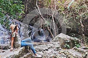 A woman sitting on the rock in front of waterfall