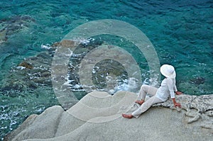 Woman sitting on the rock near the sea