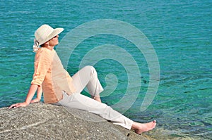 Woman sitting on the rock near the sea