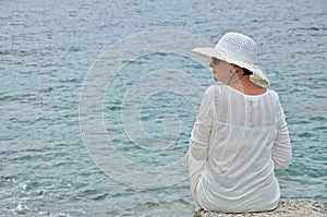 Woman sitting on the rock near the sea