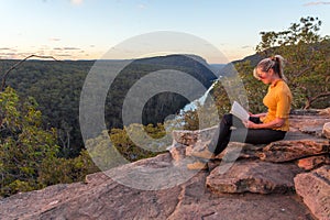 A woman sitting on a rock reading in nature