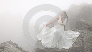 Woman sitting on rocks in fog
