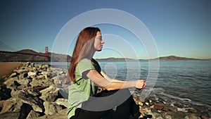 Woman sitting on rocks beside the Golden Gate Bridge