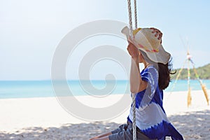 Woman sitting on rope swing at tropical beach
