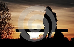Woman sitting on rural bench at dawn photo