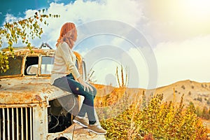 Woman sitting on rusty old classic truck.