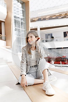 A woman is sitting in a shopping mall, laughing and smiling. Young blogger girl, close-up portrait with natural makeup.