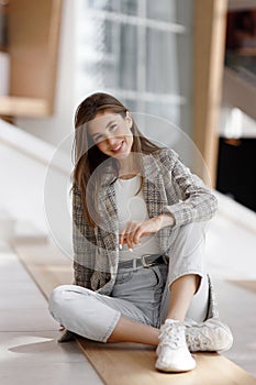A woman is sitting in a shopping mall, laughing and smiling. Young blogger girl, close-up portrait with natural makeup.