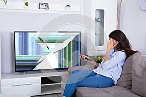 Woman Sitting On Sofa With Broken Television