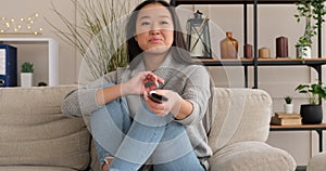 Woman sitting on sofa changing tv channel