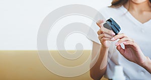 Woman sitting on the sofa, checking her health by using the oxygen level measuring device