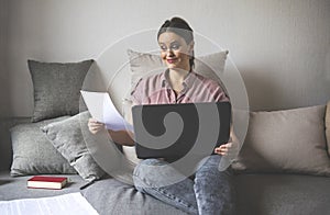 Woman sitting on the sofa with a document laptop with a joyful expression on his face , girl smiling