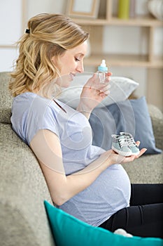 woman sitting on sofa at home holding baby shoes