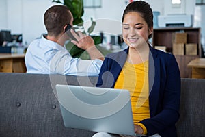 Woman sitting on sofa using laptop