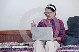 woman sitting on the sofa while working on computer on her lap