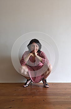 Woman sitting squatting in front of ura wall