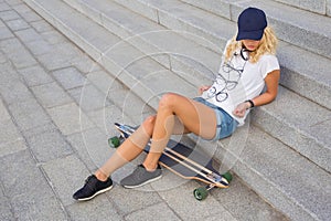 Woman sitting on stairs with longboard