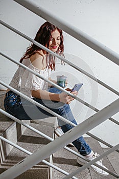 Woman sitting on stairs looking at messages on her smartphone