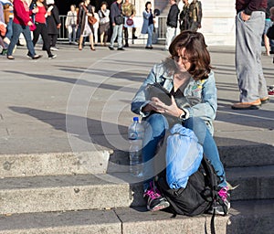 Woman sitting on the stairs reading a message on mobile phone