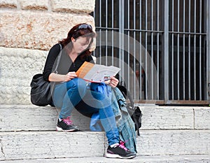 Woman sitting on the stairs and sees the map