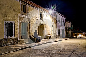 Woman sitting on a stone bench in an ancient village at night,