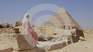 Woman sitting on a stone. The Great Pyramids of Giza in Egypt.