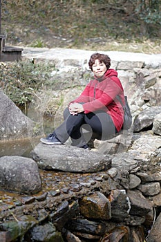 Woman sitting on the stone by the river, adobe rgb