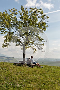 Žena sedící na letním kopci poblíž Liptovského Trnovce, Slovensko.