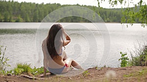 Woman sitting and sunbathing on the lake shore