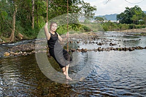 Woman sitting on a swing along the stream Swing your feet through the water slowly and happily