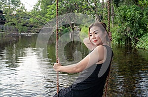 Woman sitting on a swing along the stream Swing your feet through the water slowly and happily