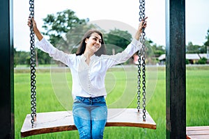 Woman sitting on a swing and holding her hand at the chain