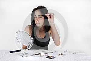 Woman sitting at a table, applying make-up in a sm