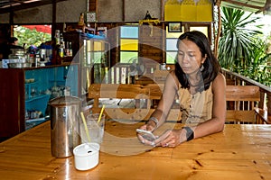 Woman sitting at table in cafe holding cell phone