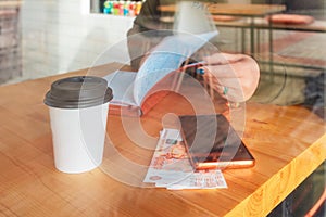 A woman is sitting at a table in cafe and working. Hands close up. The concept of business and freelance