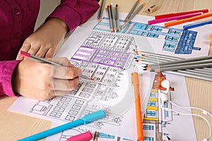 Woman sitting at table with coloring pictures for adults