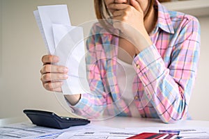 The woman sitting on the table in the house is worried and thinks heavily about the bill on hand and the expenses and debt that