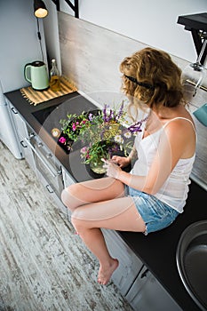 Woman is sitting on a table in the kitchen
