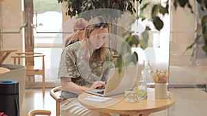 Woman sitting at table with laptop in cafe