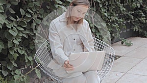 Woman sitting at table with laptop in park