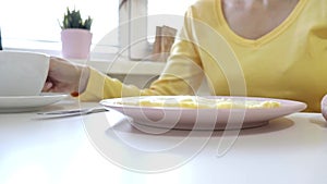 Woman sitting by the table ready for eating an omlet and drinking coffee or tea for breakfast at home or restaurant
