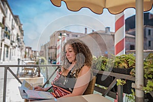 pretty woman sitting at the table of a restaurant on the edge of the little unknown canals of venice photo