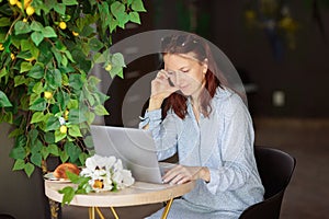 Woman sitting at table, using laptop computer while having coffee in cafe