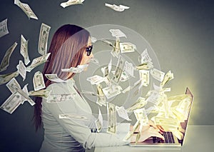 Woman sitting at table using working on a laptop computer making money