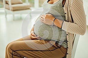 Woman sitting and touching her pregnant belly