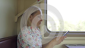 A woman, sitting in a train compartment, uses the Internet in a smartphone during the trip