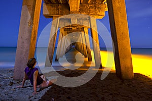 Woman sitting under pier at night